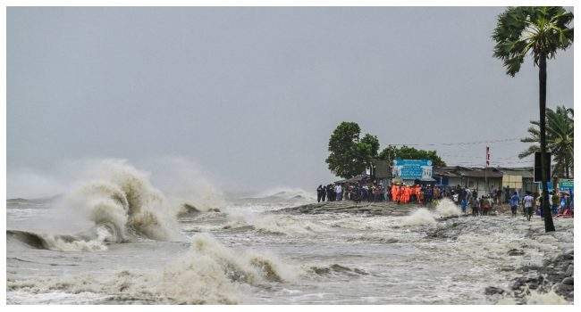 People gather along the sea shore amid rainfall in Kuakata on May 26 2024 ahead of cyclone Remals