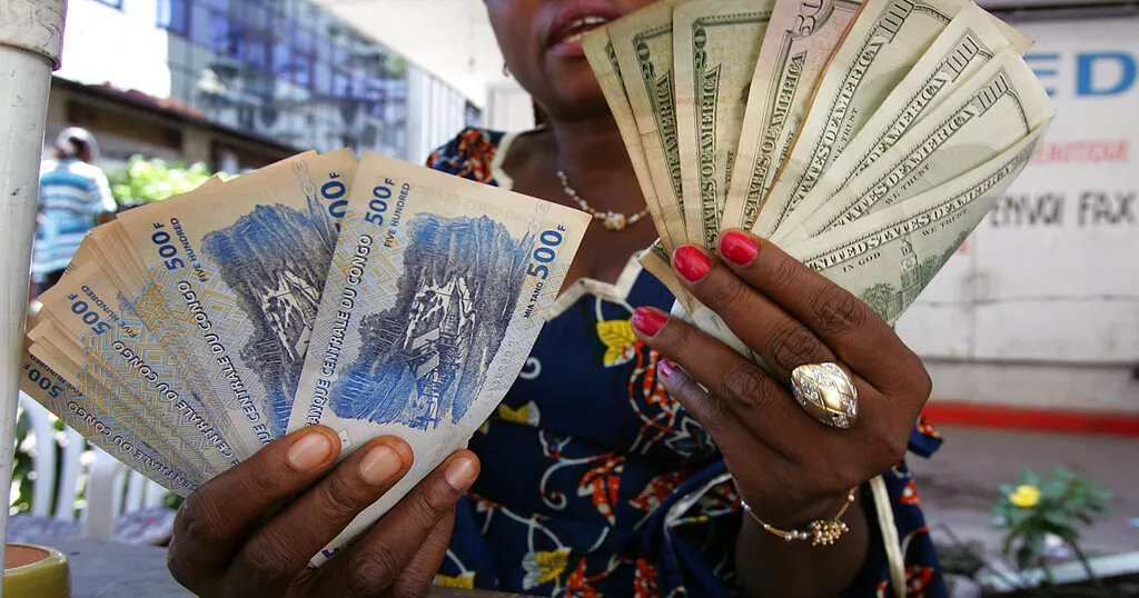 A currency trader displays US dollars and Congolese francs at a local market in Kinshasa Congo Thursday November 9 2006 AP