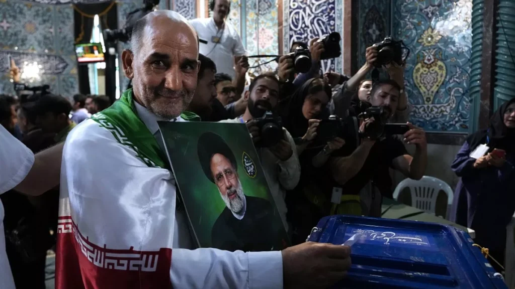 a man casts his ballot during the presidential election as he holds a picture of the late president ebrahim raisi in a polling station in tehran iran friday june 28 2024