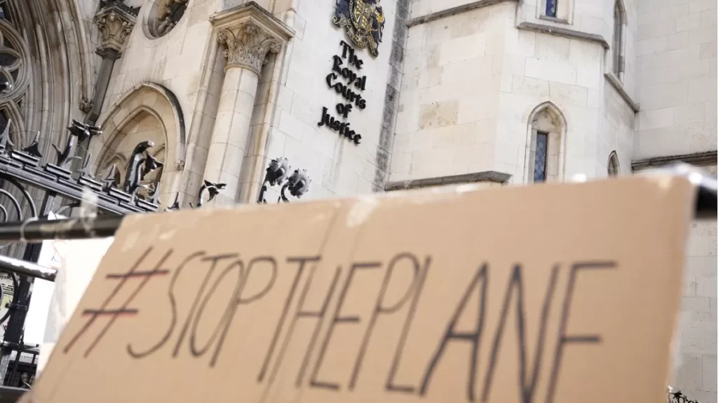 A placard left outside the High Court where the ruling on Rwanda deportation flights is taking place, in London Monday, June 13, 2022