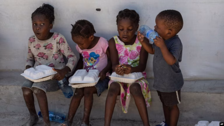 children hold food rations at a shelter for families displaced by gang violence in the tabarre neighborhood of port au prince haiti may 19 2024 ap