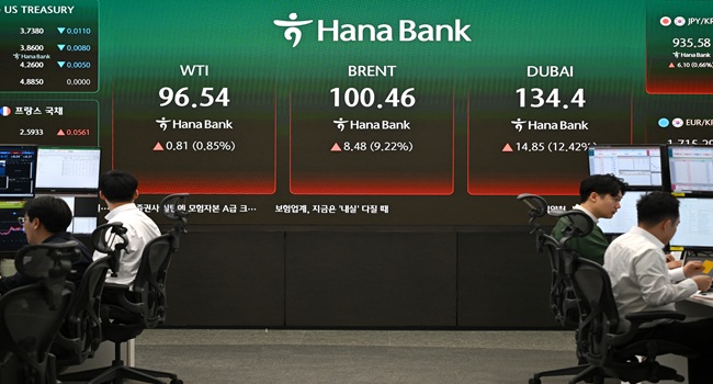 Currency dealers monitor exchange rates as an electronic screen shows the prices of WTI (L), Brent crude (C) and Dubai crude (R) in a foreign exchange dealing room at the Hana Bank headquarters in Seoul on March 13, 2026. (Photo by Jung Yeon-je / AFP)