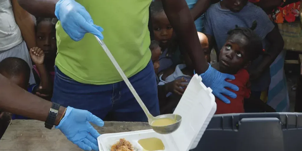 a server ladles soup into a container as children line up to receive food at a shelter for families displaced by gang violence in port au prince haiti march 14 2024 a server ladles soup into a container as children line up to receive food at a shelter for families displaced by gang violence in port au prince haiti march 14 2024
