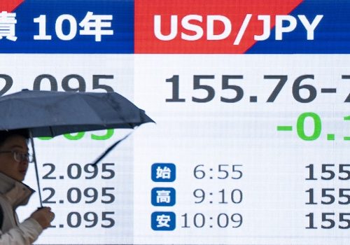 A pedestrian walks past an electronic quotation board displaying the foreign exchange rate of the Japanese yen against the US dollar (R) along a street in Tokyo on February 25, 2026. (Photo by Kazuhiro NOGI / AFP)